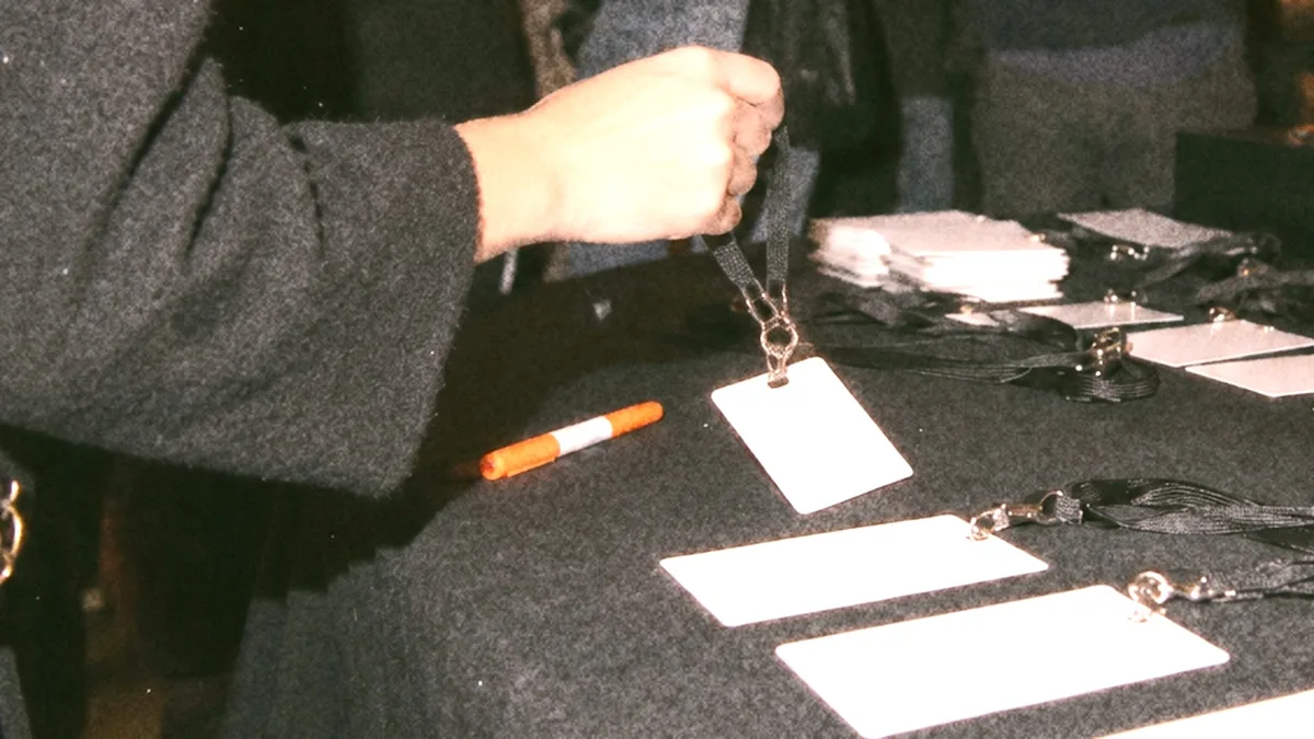 A hand writing a name badge at an event check-in table at night