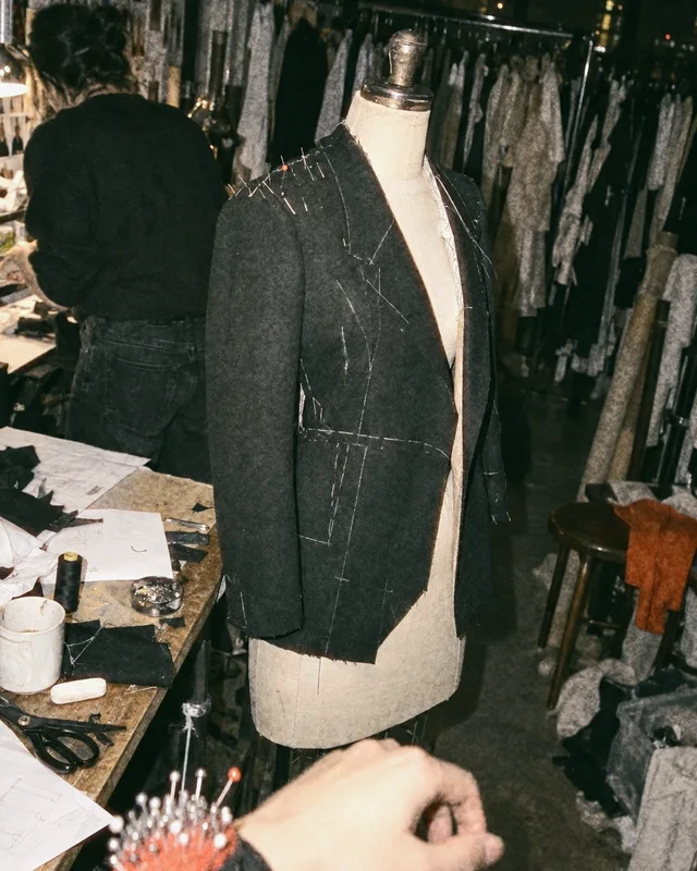 A wool jacket pinned on a dress form during a late fitting