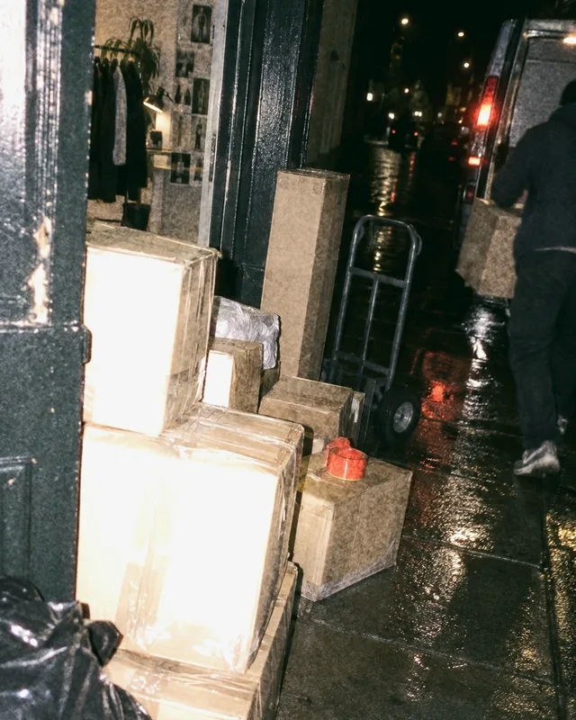 Taped cartons on a wet pavement at night, waiting for the courier