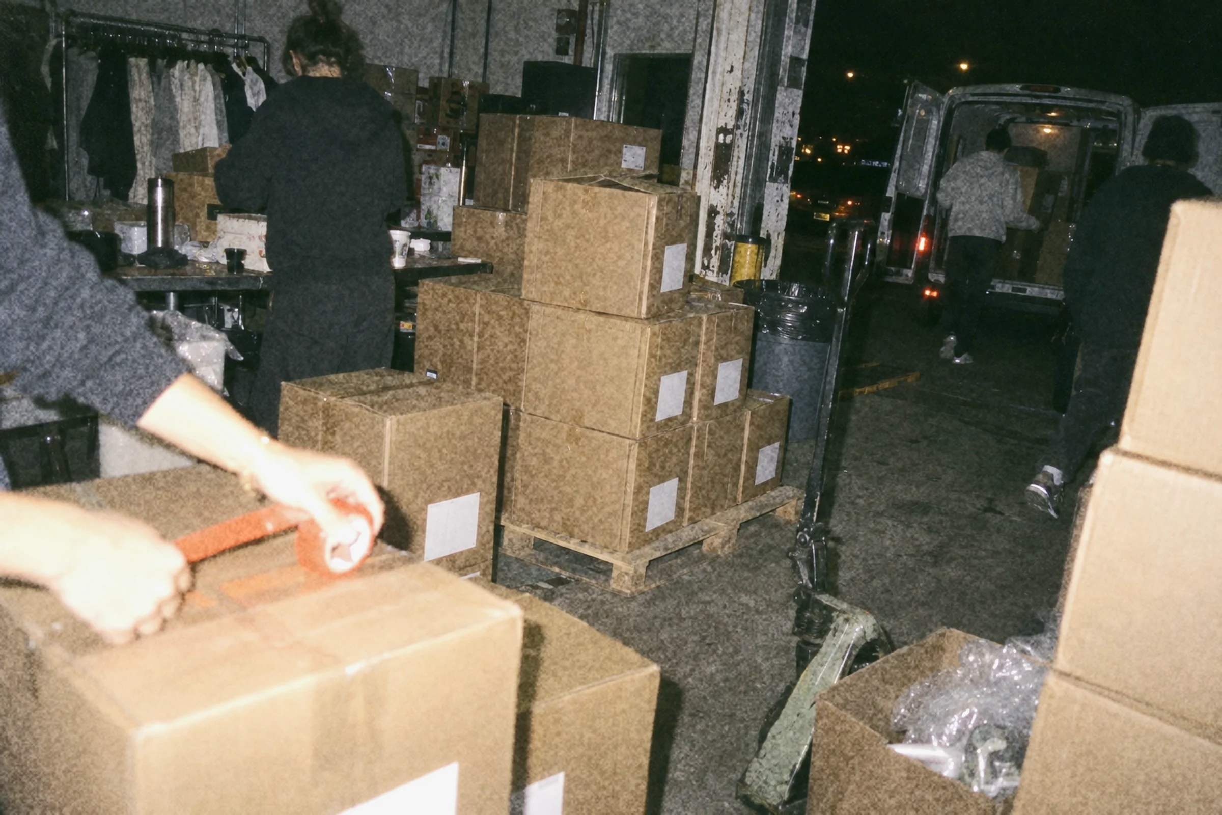 A garment wrapped in tissue in an open carton, an orange swing tag laid on top