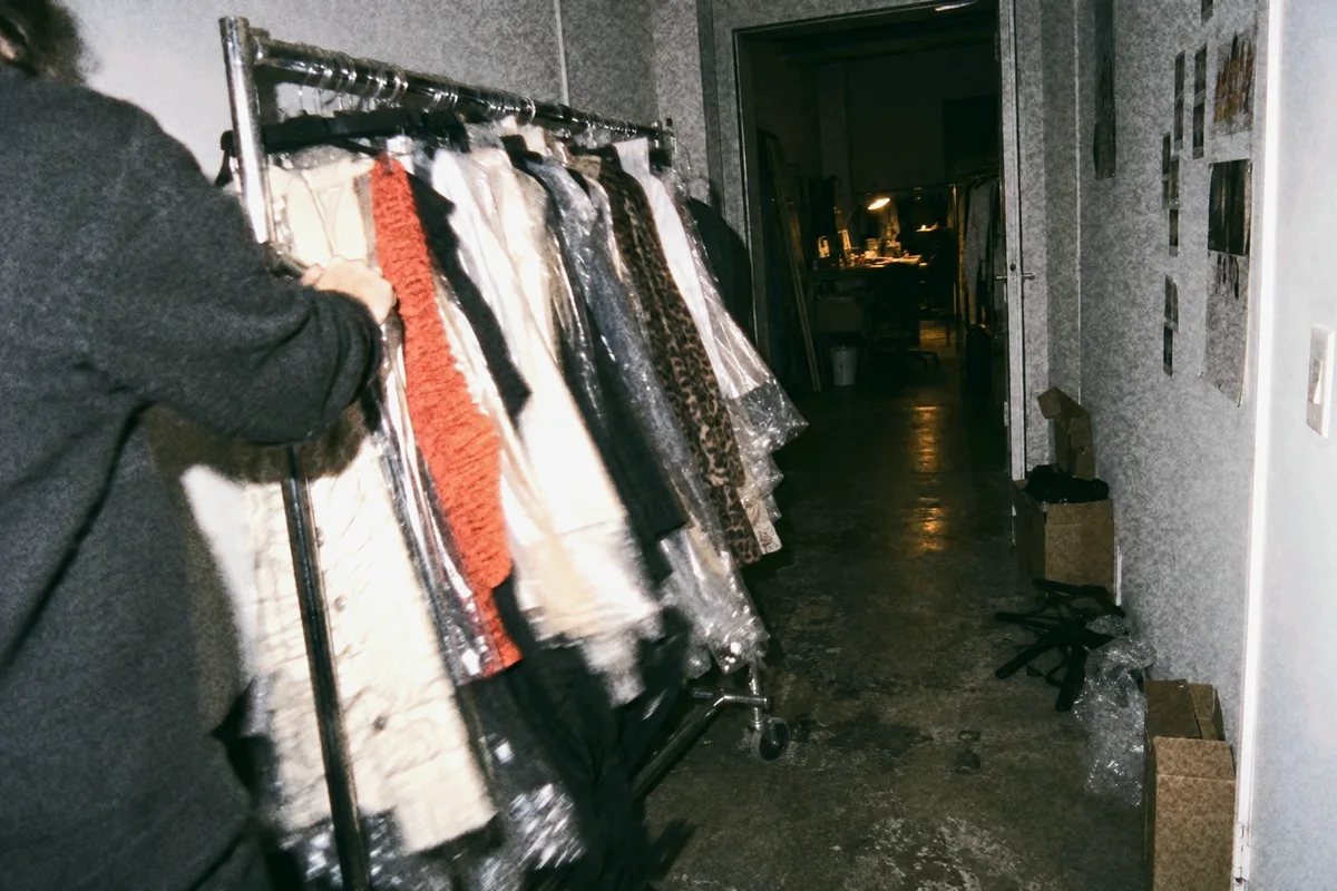 A loaded garment rail pushed fast down a corridor at night