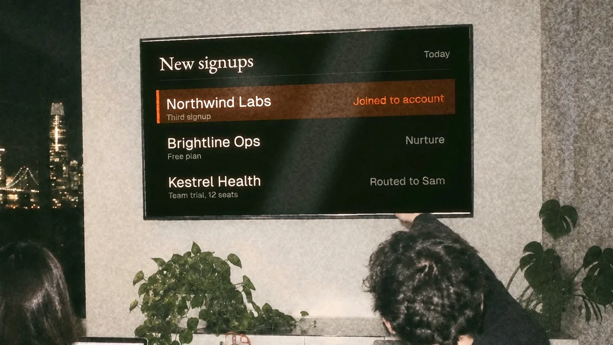 New signups arriving on a wall screen in an office at night, one highlighted in orange